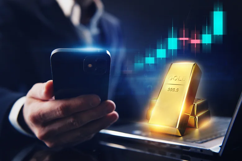 Businessman using smartphone, gold bars and rising stock chart: digital trading concept